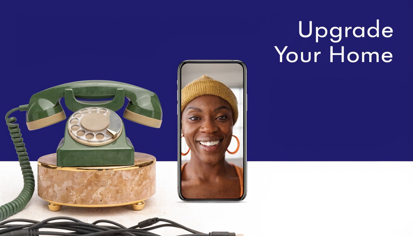 An antique rotary phone sits next to a modern smartphone displaying a woman on a video call.