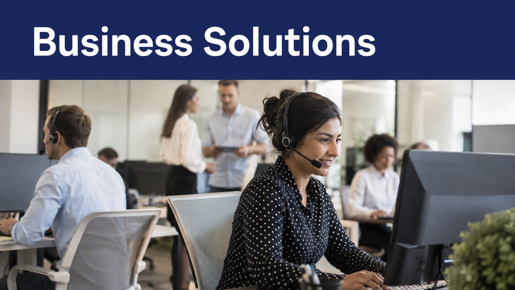 A diverse team of office workers wearing headsets while working at their computers in a modern office.