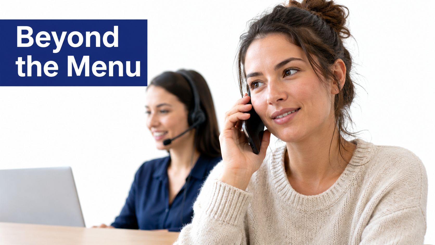 A friendly customer support representative speaking on a mobile phone with a colleague working in the background.